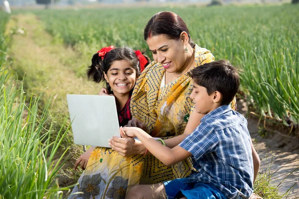 Mor med barn som använder bärbar dator på jordbruksfältet — Stockfoto