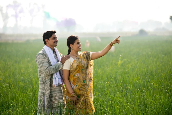 Glückliches indisches Bauernpaar begutachtet Ernte auf landwirtschaftlichem Feld — Stockfoto