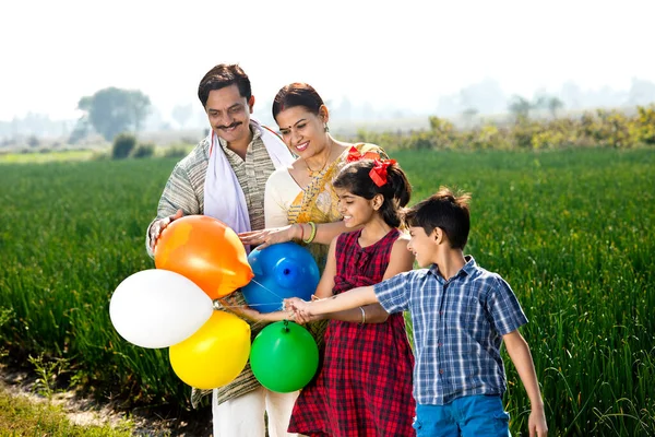 Família indiana feliz de fazendeiro com balões no campo agrícola — Fotografia de Stock