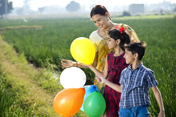 Família indiana feliz de fazendeiro com balões no campo agrícola — Fotografia de Stock