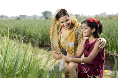 Tarımsal alanda cep telefonu kullanan taşralı anne ve kız