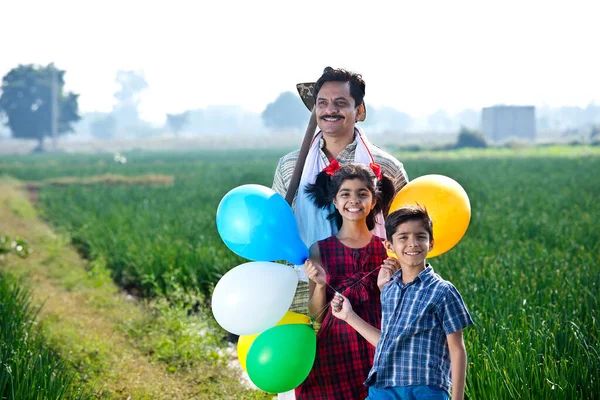 Glückliche indische Bauernfamilie mit Luftballons auf dem Feld — Stockfoto