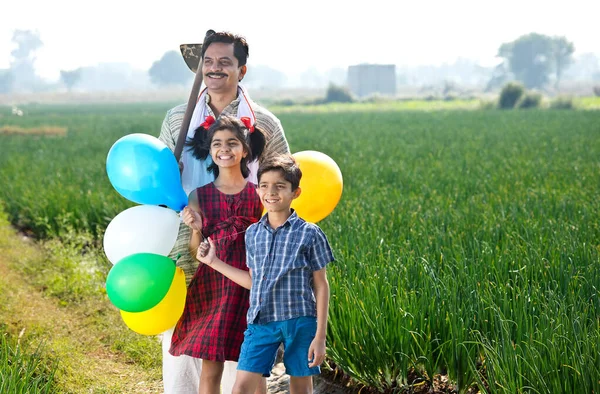 Glückliche indische Bauernfamilie mit Luftballons auf dem Feld — Stockfoto