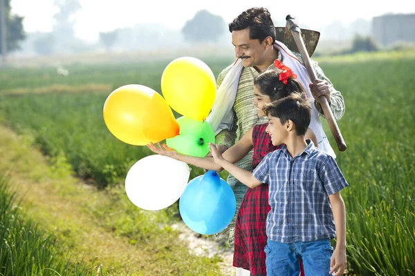 Família indiana feliz de fazendeiro com balões no campo agrícola — Fotografia de Stock