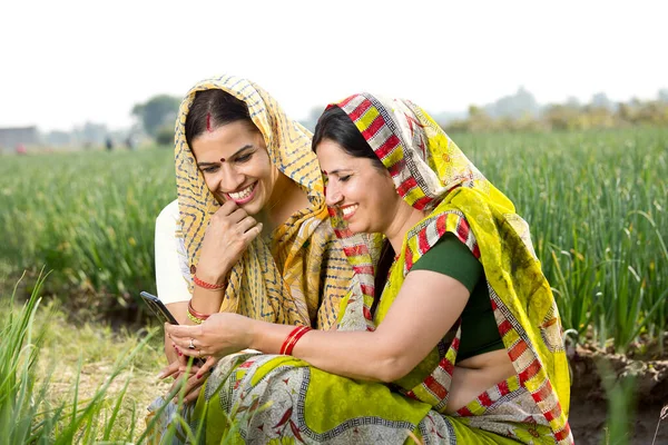 İki mutlu kırsal kadın tarım alanında telefon kullanıyor.