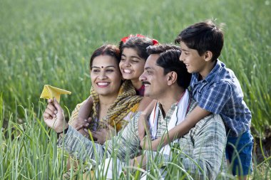 Kırsal kesim ailesi tarıma kağıt uçak fırlatıyor.