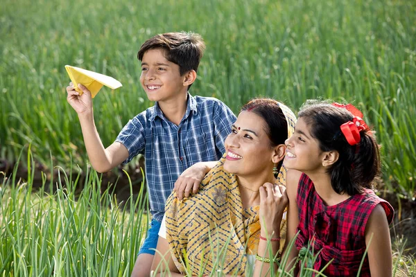 Família rural com menino jogando avião de papel no campo agrícola — Fotografia de Stock