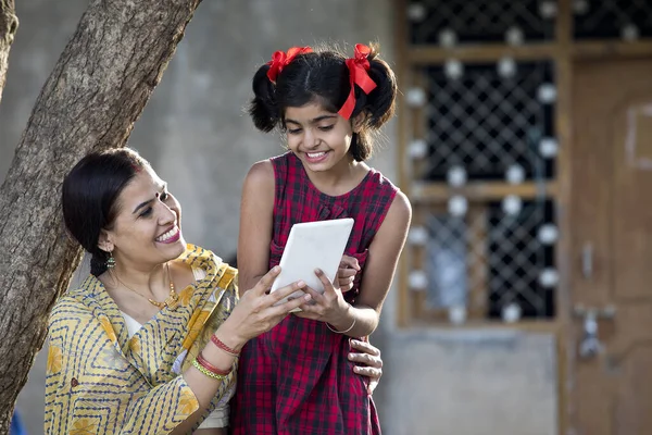 农村女孩和母亲在村子里用数码平板电脑 — 图库照片