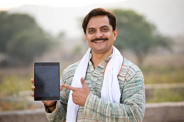 Happy rural Indian farmer showing digital tablet screen