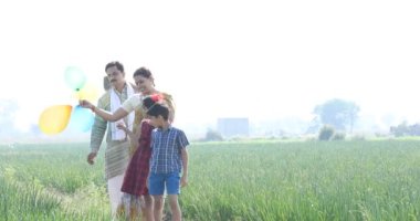 Tarım tarlasında balonları olan mutlu Hintli çiftçi ailesi