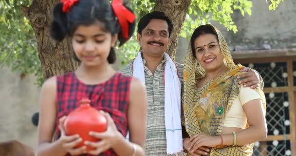 Keluarga India Pedesaan dengan anak perempuan yang terkejut memegang celengan — Stok Video