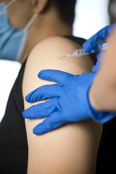 Läkare injicerar vaccin i patientens arm Stockbild