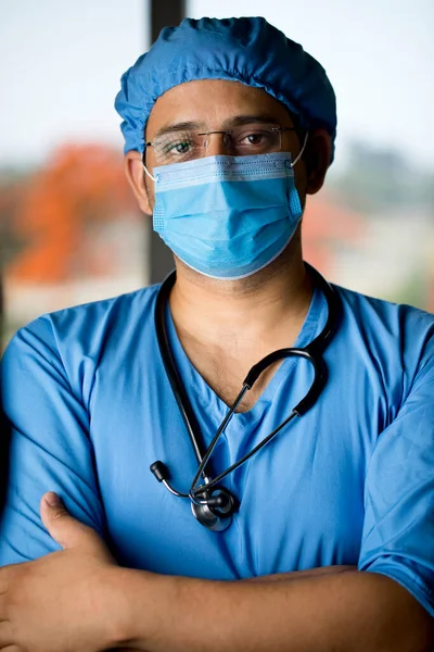 Chirurgo maschio in maschera facciale con braccia Foto Stock