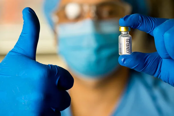 Läkare som håller levande vaccin och ger tummen upp Royaltyfria Stockfoton
