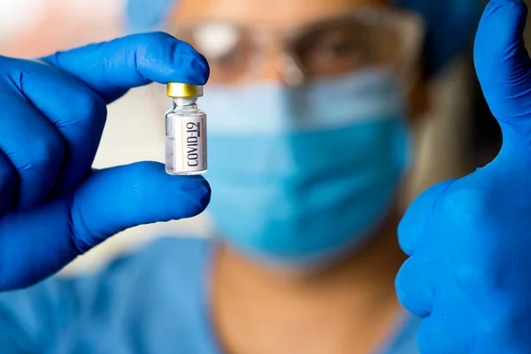 Az orvos kovid vakcinát tart és feladja a hüvelykujját. Stock Kép