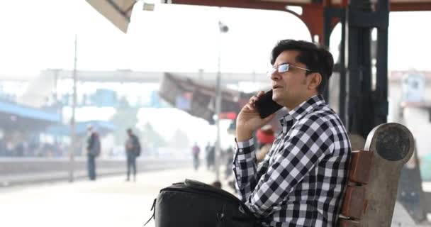 Hombre usando el teléfono mientras espera en la plataforma de la estación de tren — Vídeo de stock