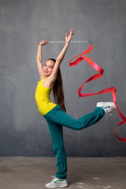 Kurdeleli jimnastikçi. Jimnastikçi bacağını kaldırıyor. İyi esneme. Eşofmanlı bir kadın. Jimnastikçi çorap çeker