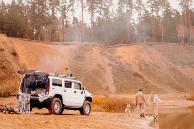Rusya, Kazan-Ekim 16, 2019: Kumda beyaz bir cip. Fotoğraf çekimi için güzel tasarlanmış bir araba. Gölde beyaz Hummer. Göl kenarında yürüyen bir çift sevgili.