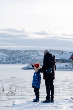 Baba ve oğul kışın denizi izliyorlar. Kış denizinin yanında yürü. Aile Kış Gezisi Denize Seyahat. Çocuklarla İskandinav gezisi