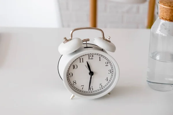 Çalar saat ve masada su olan cam şişe. Biraz su içme zamanı. Günlük alışkanlıklar. İyi alışkanlıklar..