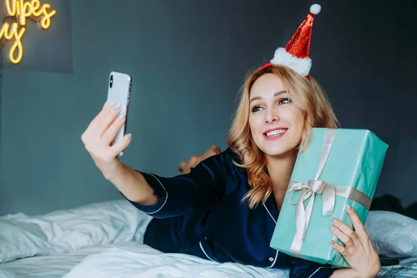 Noel hediyeli bir kadın. Noel 'i telefonla kutluyoruz. Noel boyunca Skype sohbeti. Kız teslimat yoluyla bir hediye aldı. Kız telefon aracılığıyla akrabalarına mutlu noeller diliyor.