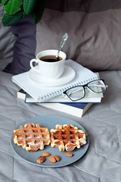 Viennese waffles and coffee in bed. Morning breakfast. Waffles with almond flour. A healthy snack. Still life on a gray bed
