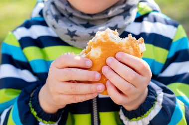 Hamburgerler bir çocuğun ellerinde. Yürüyüşte atıştırmalık.
