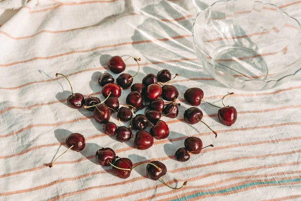 Cerejas doces maduras em uma tigela e espalhadas em uma mesa de madeira branca. Vista de cima. Cerejas lavadas. Bagas saudáveis no verão. Colheita de bagas — Fotografia de Stock