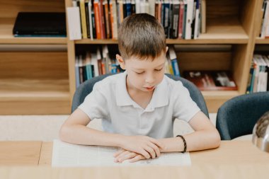 Okuldaki öğrenci masada oturup kütüphanede kitap okuyor. Ödevimi hazırlıyorum. İyi bir öğrenci. Çocuk okumayı seviyor. Okulda boş yer var.