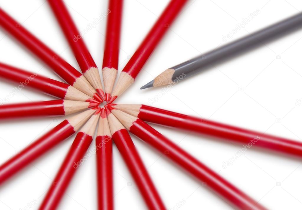 Close up of a black pencil standing out from a circle formed by 