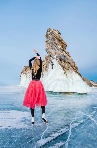 Genç ve güzel bir kadın Sibirya 'daki donmuş Baykal gölünde buz patenlerinin üzerinde duruyor.