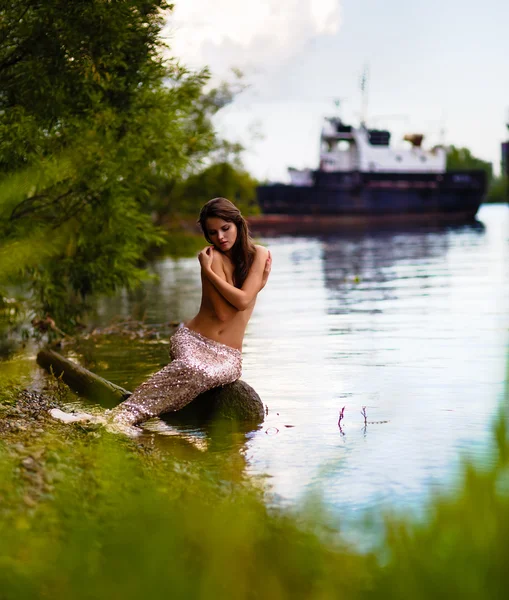 Kaunis alasti, seksuaalinen merenneito joen rannalla — kuvapankkivalokuva