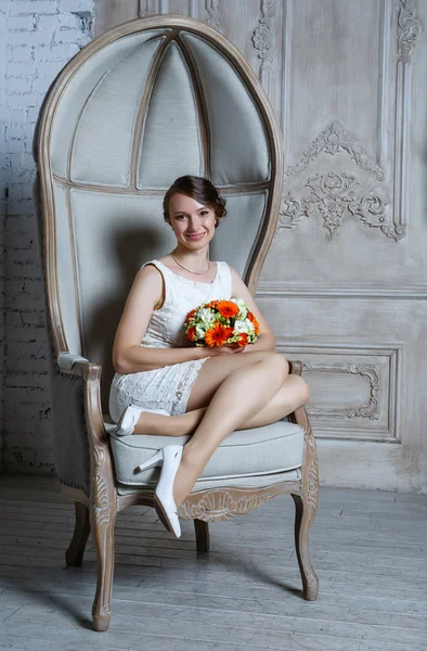 Young beautiful sexy woman with flowers in a chair on a couch — Stock Photo, Image