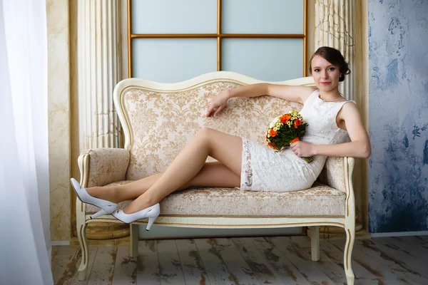 Young beautiful sexy woman with flowers in a chair on a couch — Stock Photo, Image