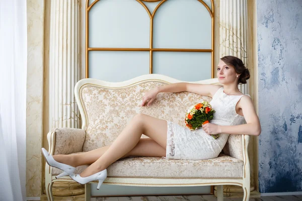 Young beautiful sexy woman with flowers in a chair on a couch — Stock Photo, Image