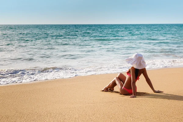 La jeune femme en bikini avec un chapeau sur une plage de sable — Photo