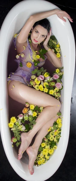 Brunet girl in bath with flowers