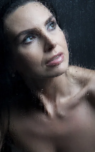 Jeune femme mélancolique et triste à la fenêtre sous la pluie — Photo