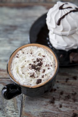 Marshmallow ahşap arka plan üzerine bir fincan sıcak kahve