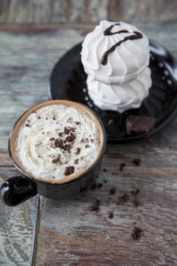 Marshmallow ahşap arka plan üzerine bir fincan sıcak kahve