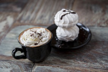 Marshmallow ahşap arka plan üzerine bir fincan sıcak kahve