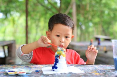 Küçük sevimli Asyalı erkek bebek, oyuncak bebeğe resim yapıyor..