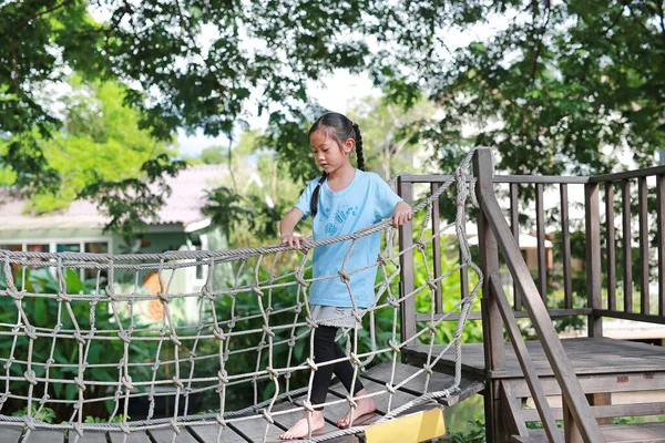 サスペンション木製の橋で遊んでアジアの小さな子供の女の子 ロープブリッジを歩く子供公園の遊び場での設備 — ストック写真