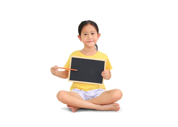 アジアの小さな子供の女の子座っていると保持色鉛筆ポイント上の黒ボード孤立した上の白い背景 — ストック写真