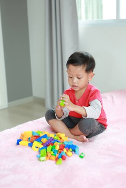 Asyalı küçük bebek renkli plastik bloklar oynuyor ve yatakta yatıyor..