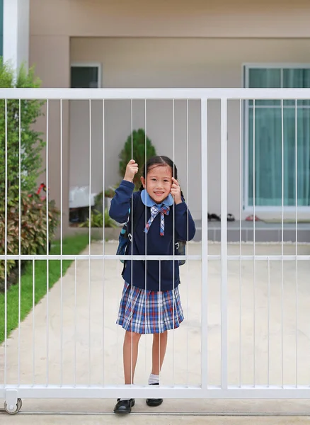 早上上学前 穿着幼稚园制服的亚洲小女孩在家门口的篱笆边微笑着 — 图库照片