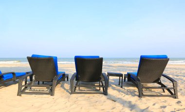 Kumsaldaki kumsal sandalyeleri Bulutlu mavi gökyüzü ve güneşli