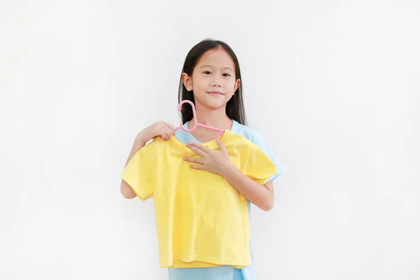 白い背景に黄色のシャツをしようとしているアジアの女の子の肖像 — ストック写真