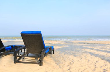 Kumsaldaki kumsal sandalyeleri Bulutlu mavi gökyüzü ve güneşli