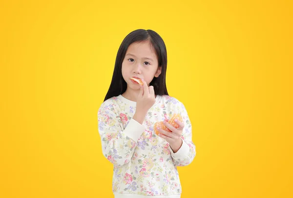 Pouco Asiático Menina Comer Laranja Fruta Isolado Amarelo Fundo Com — Fotografia de Stock